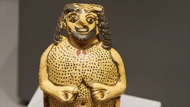 Gold-decorated antique figure with striking facial features in a museum, Archaeological Museum,