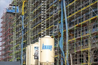 Large construction site, scaffolded shell of an office building complex, air hoses for construction