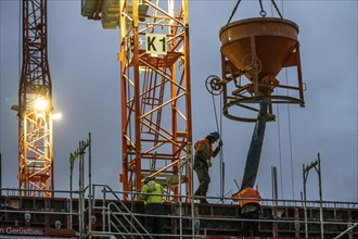 Concrete work, at dusk, on a large construction site building a residential and commercial complex,