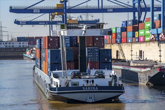 Container cargo ship enters the port basin of the Logport, gantry cranes in the Container Handling