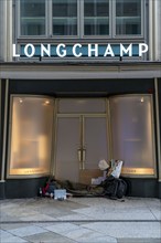 Camp of a homeless person, in the entrance of a Longchamp leather goods shop, at the Domplatte, in