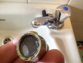 Calcified, clogged faucet aerator, limescale residue clogs the strainer of the faucet aerator