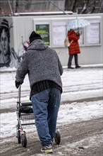 Winter in the city, man with rollator finds his way through snowy street, slush, Germany, Europe