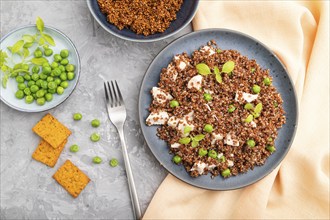 Quinoa porridge with green pea and chicken on ceramic plate on a gray concrete background and