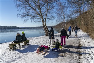 Winter in the Ruhr area, Lake Baldeney, snow-covered, partly frozen lake, walkers on the lakeside