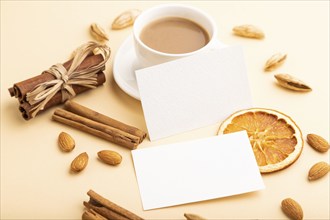 Composition of white paper business cards, almonds, cinnamon and cup of coffee. mockup on orange