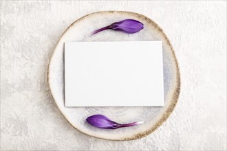 White paper invitation card, mockup with crocus flowers on ceramic plate and gray concrete