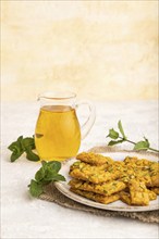 Traditional iranian dessert sohan with glass of green tea on a gray concrete background and linen