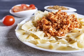 Farfalle bolognese pasta with minced meat on black wooden background. close up, selective focus