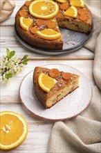 Orange cake and a cup of coffee on a white wooden background and linen textile. Side view, close up