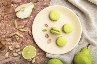 Green macarons or macaroons cakes with cup of coffee on a brown concrete background and linen