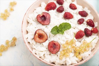 Rice flakes porridge with milk and strawberry in ceramic bowl on white concrete background and blue