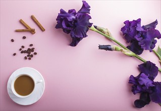 Purple iris flowers and a cup of coffee on pastel pink background. Morninig, spring, fashion