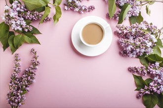 Purple lilac flowers and a cup of coffee on pastel pink background. Morninig, spring, fashion