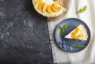 A piece of peach cheesecake on a blue ceramic plate with blue flowers on a linen napkin on a black