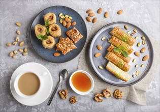 Set of various traditional arabic sweets: baklava, kunafa, basbus in ceramic plates on a gray