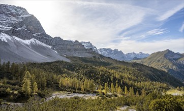 Mountain panorama with steep rocky peaks, yellow-coloured larches in autumn, hike to the summit of