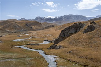 River Kol Suu winds through a mountain valley with hills of yellow grass, Naryn Province,