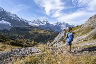 Mountaineers on a hiking trail, mountain panorama with rocky steep peaks, yellow-coloured larches