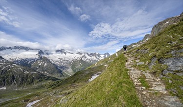 Mountaineer on hiking trail in picturesque mountain landscape, mountain peak with snow and glacier