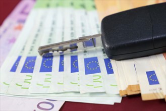 Euro banknotes and car keys as a symbol for car costs