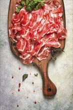 Prosciutto on a cutting board, top view, appetizer, breakfast, spices and herbs