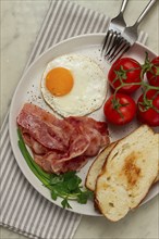 Breakfast, fried egg, bacon and bread, with cherry, on a light background, homemade, no people