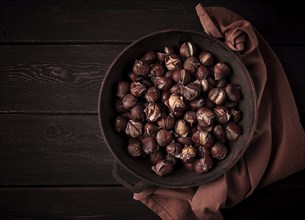 Roasted chestnuts, in an iron pan, wooden table, top view, no people, rustic style