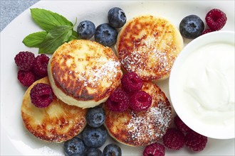 Breakfast, cottage cheese cakes, with fresh berries, and sour cream, top view, close-up, no people