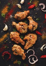 Fried chicken legs, breaded, with spices and herbs, on a dark background, vertical, no people,