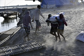 Public Works Department (PWD) of Assam labourer carrying sand bag to boat in Beki River to make