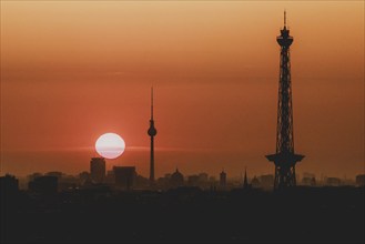 The sunrise emerges behind the city skyline with the television tower and the radio tower in