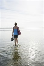 Woman walking through the mudflats, Wyk, Föhr, North Frisia, Schleswig-Holstein, Germany, Europe