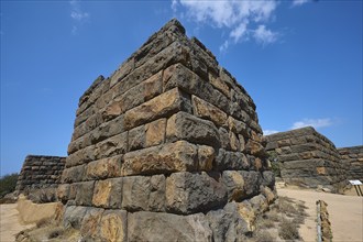 Detailed view of a corner of an ancient ruined wall in an arid landscape under a clear blue sky,