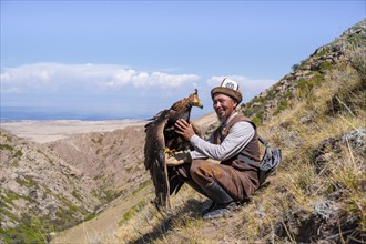 Traditional Kyrgyz eagle hunter with eagle in the mountains, near Kysyl-Suu, Kyrgyzstan, Asia