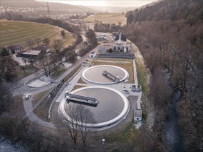 Drone shot of a sewage treatment plant with round basins in a gentle landscape at dusk, Nagold,