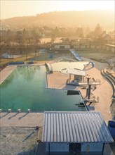 Winter sunrise over a quiet swimming pool with slide and frost-covered roof, ENCW outdoor pool