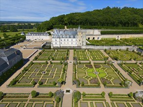 Aerial view of a castle with symmetrical, formal gardens characterised by green hedges and