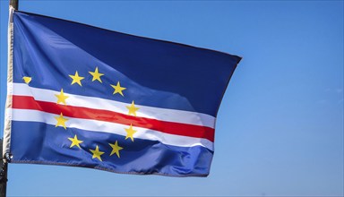 The flag of Cape Verde flutters in the wind, isolated against a blue sky