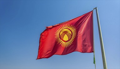 The flag of Kyrgyzstan, Kyrgyzstan, flutters in the wind, isolated against a blue sky, Asia