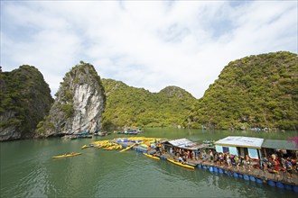 Holidaymakers queue for a kayak on a jetty, behind the karst rocks in Lan Ha Bay, Halong Bay,