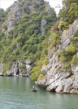 Tiny fishing boat and the huge karst rocks in Lan Ha Bay, Halong Bay, Vietnam, Asia