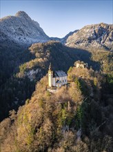 Bright morning sun shines on a church standing on a rocky cliff in front of a mountain panorama, St