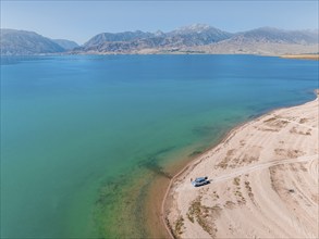 Tourists at the lake with car, aerial view, erosion landscape at the river Naryn, Toktogul