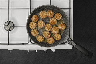 Top view of cooking meatballs in frying pan with olive oil on a gas stove