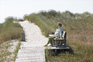 Elderly, woman sitting on bench, wooden footbridge, reed grass, circular hiking trail, nature