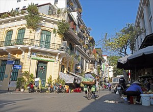 Vietnamese saleswoman with conical hat pushing her bicycle through the Old Quarter, Hanoi, Vietnam,