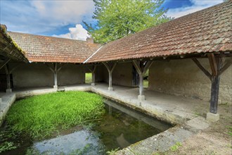 Washhouse in Montaigu-le-Blin village features a grassy basin, Allier. Auvergne-Rhone-Alpes,