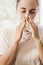 Woman in bright room uses paper towel, focus is on facial expression of discomfort, 'symbolic