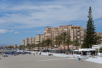 Beach promenade with high residential buildings and palm trees, summer sky, Torrox, Málaga